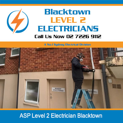 Level 2 electrician on ladder working on external wall of brick building in Blacktown